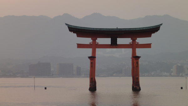 the torii gate in the water with mountains in the background